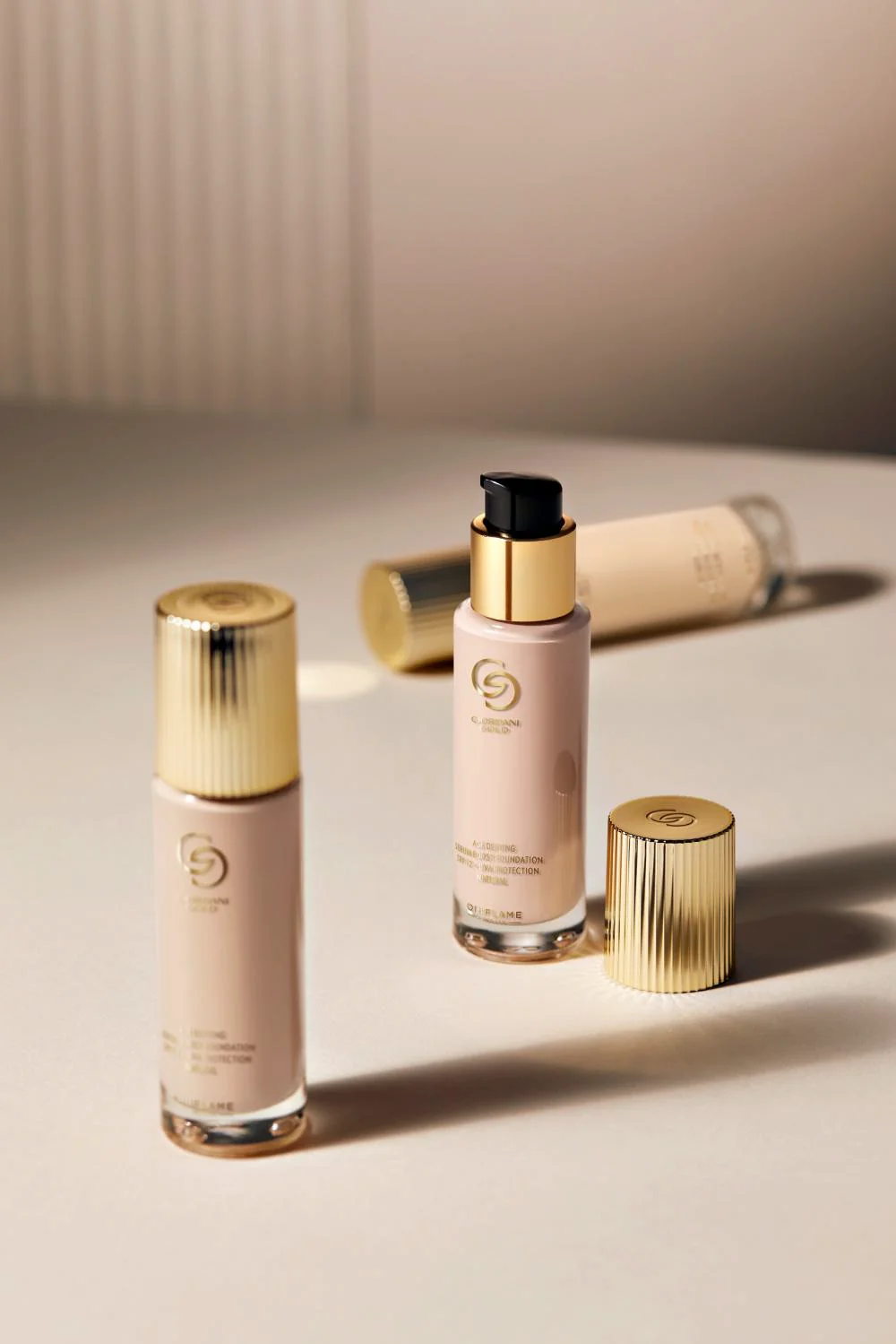 Duas embalagens da Base Antienvelhecimento Sérum Boost Giordani Gold sobre uma superfície clara, com tampas douradas.