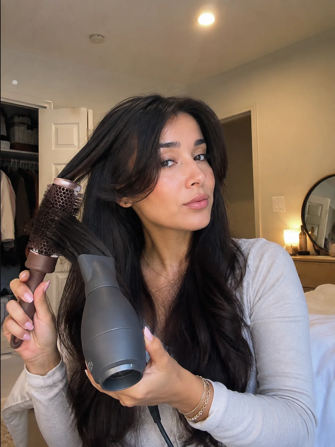 Mulher a fazer brushing com escova redonda e secador para dar volume ao cabelo.