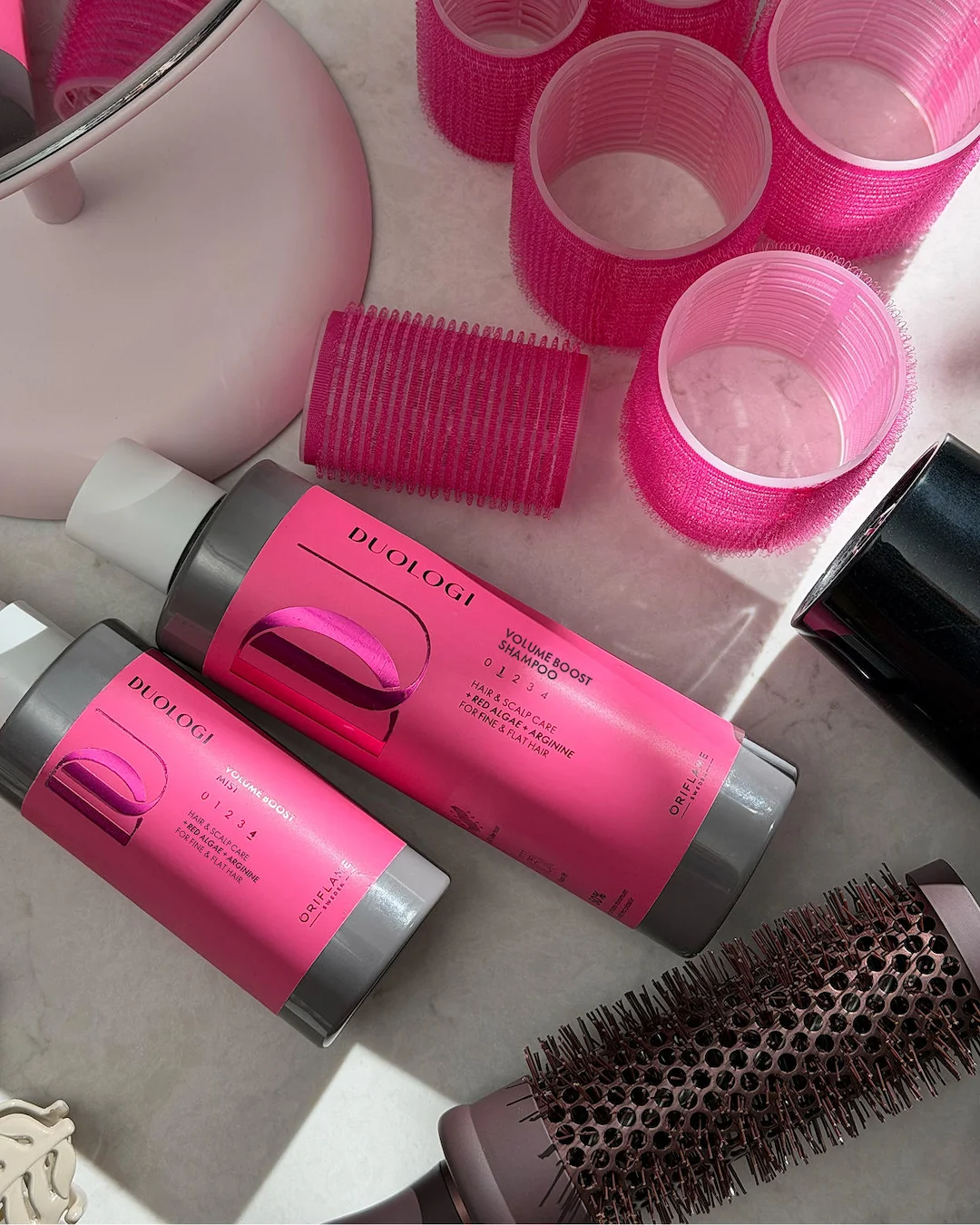 Produtos Duologi Volume Boost junto a rolos e escovas para criar volume no cabelo fino